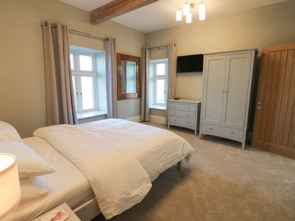 A bedroom with a bed dresser wardrobe mirror and windows at Valley View in West Witton