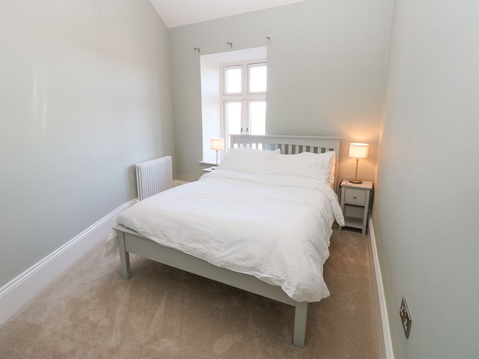 A bedroom with a double bed two bedside tables lamps a window and a radiator at Valley View in West Witton