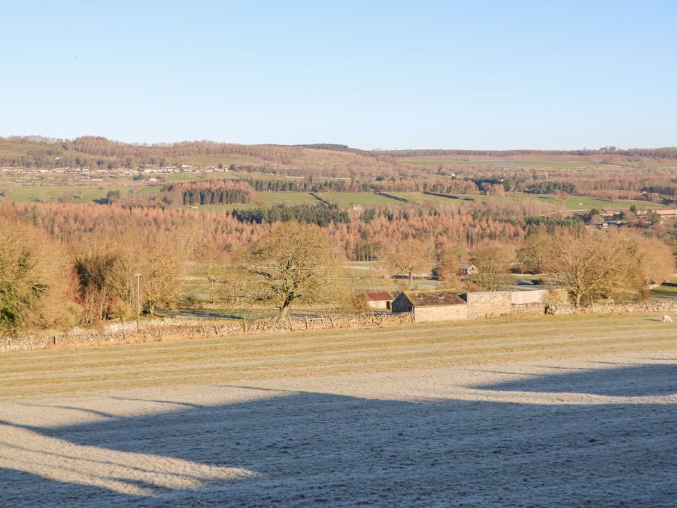 A rural landscape with fields trees and farm buildings under a clear sky at Valley View in West Witton