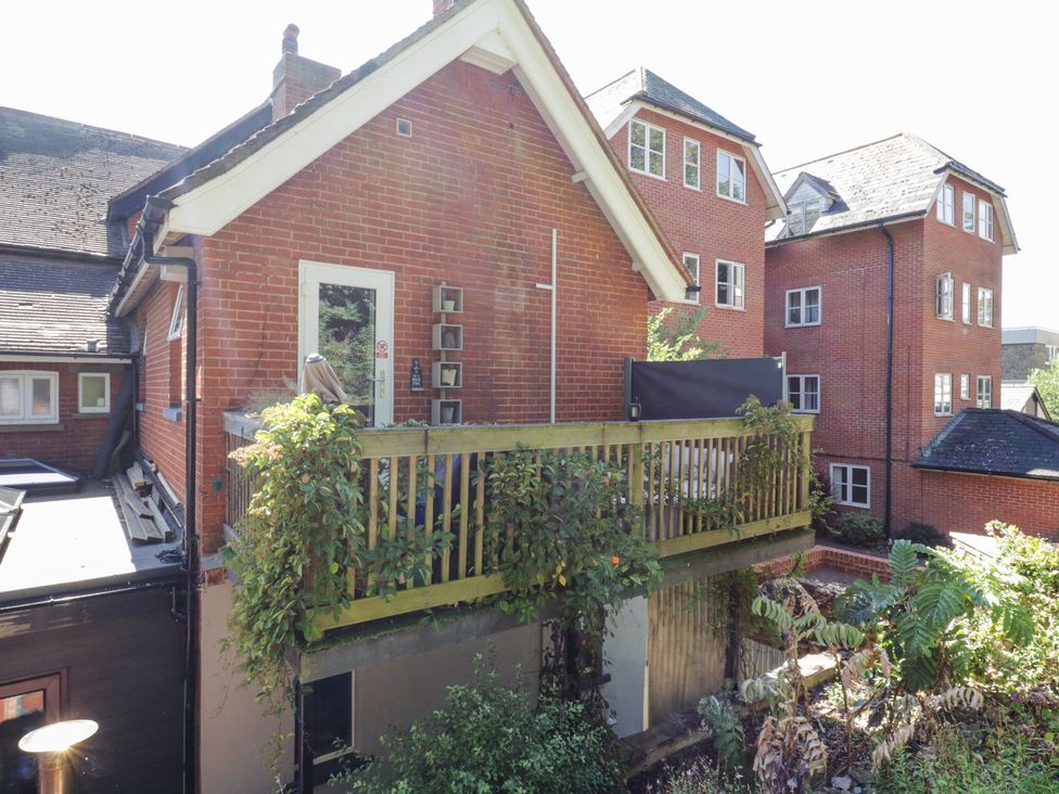 The exterior of a brick building with a wooden balcony and some plants at Saxon Lodge Cottage in Felixstowe Suffolk