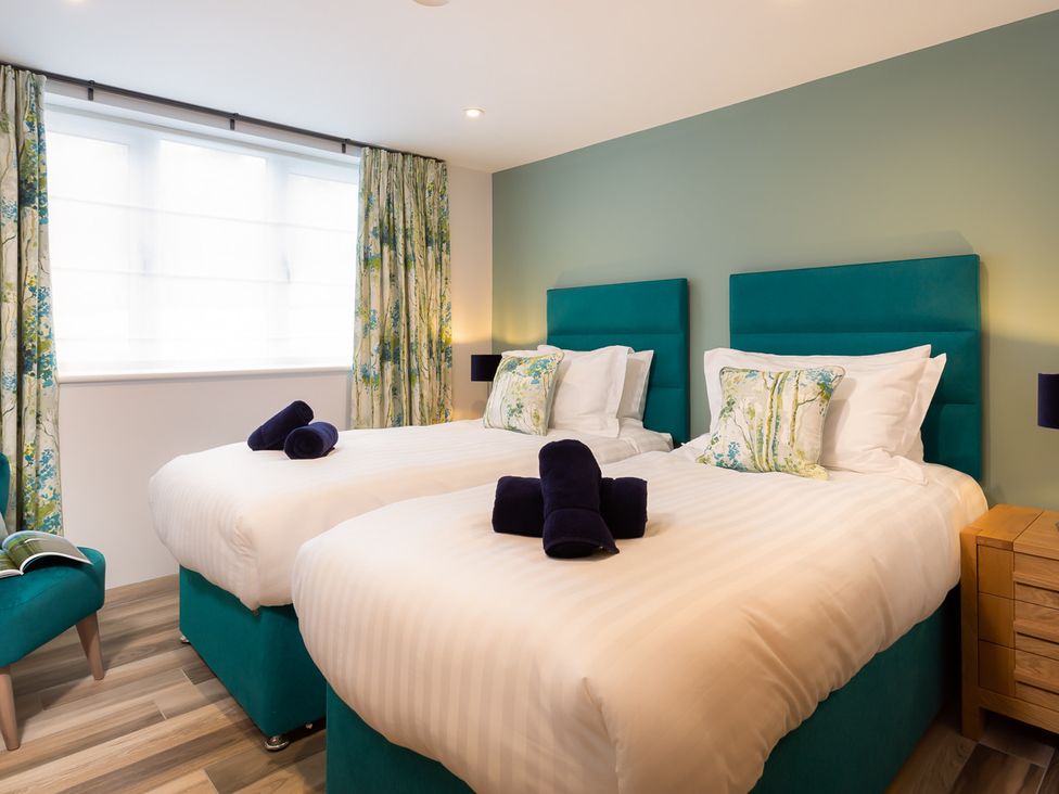A bedroom with two single beds with teal headboards and white bedding at Fell View in Keswick