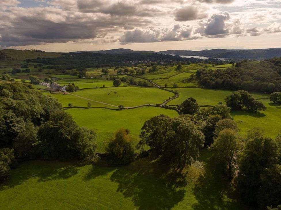 A landscape of green fields with scattered trees and distant hills under a cloudy sky at Hygge at No Eight in Windermere