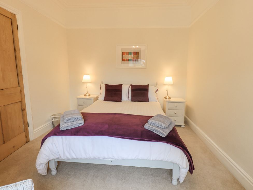 A bedroom with a double bed two bedside tables with lamps and towels at Ash Cottage in Windermere