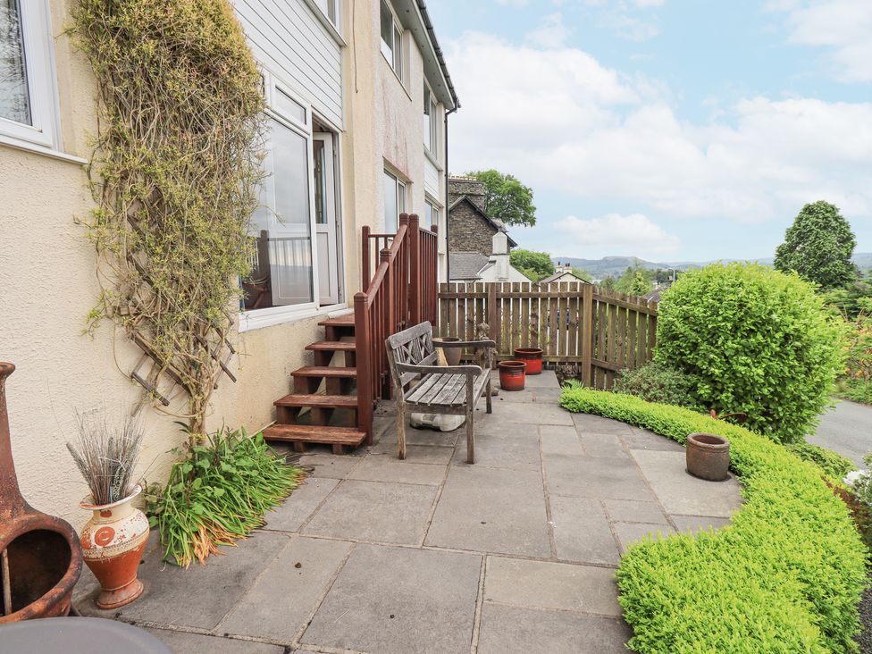 A paved patio with wooden bench steps and potted plants next to a house at Fellcroft in Troutbeck