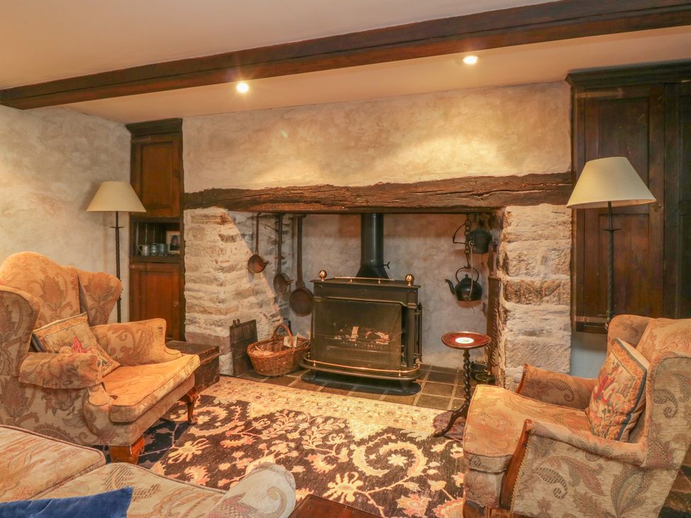 A living room with a fireplace wood stove two armchairs and lamps at The Pend in Whithorn