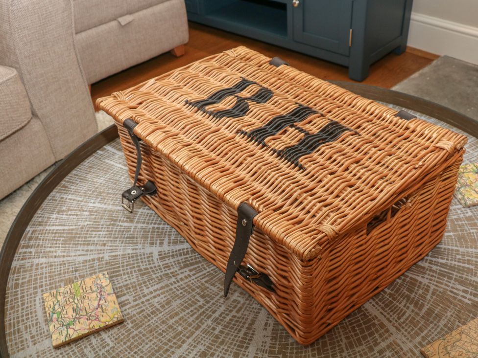A woven wicker basket with leather straps on a round wooden table in a living room at Brookhouse Castleton Peak District