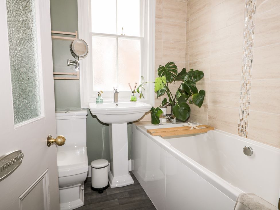 A bathroom with a toilet, pedestal sink, bathtub, plant, and frosted window at 39 West Street in Scarborough
