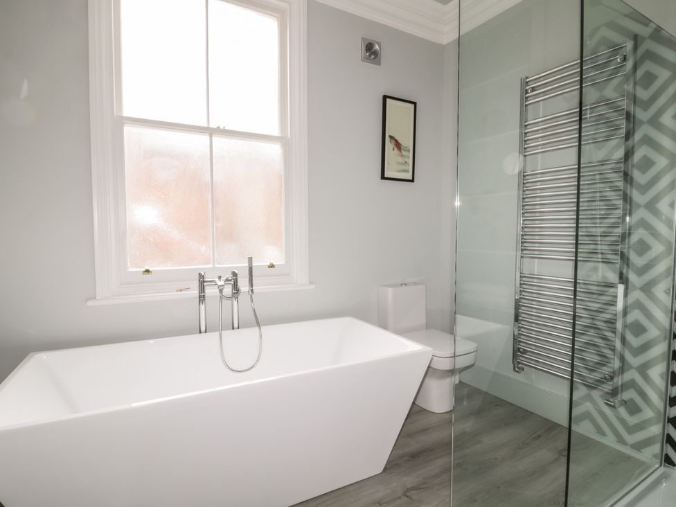 A bathroom with a freestanding bathtub a toilet a towel radiator and a window at 39 West Street Scarborough