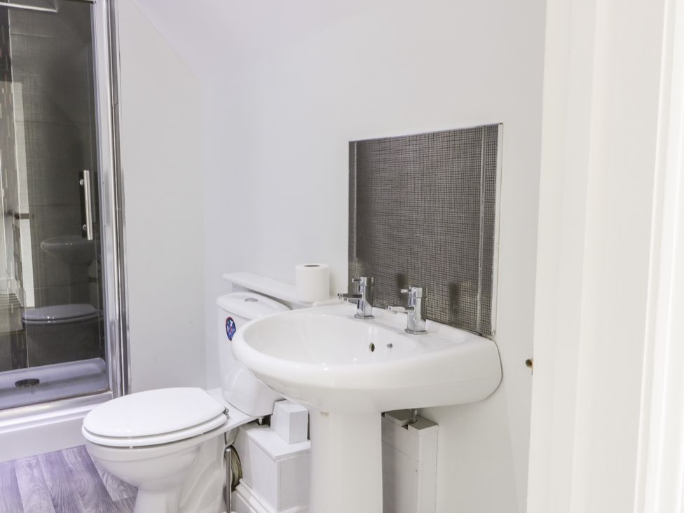 A bathroom with a toilet and a pedestal sink next to a shower enclosure at 39 West Street Scarborough