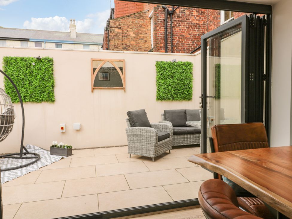 A patio with wicker chairs green wall decor and a wooden table with leather chairs at 39 West Street in Scarborough
