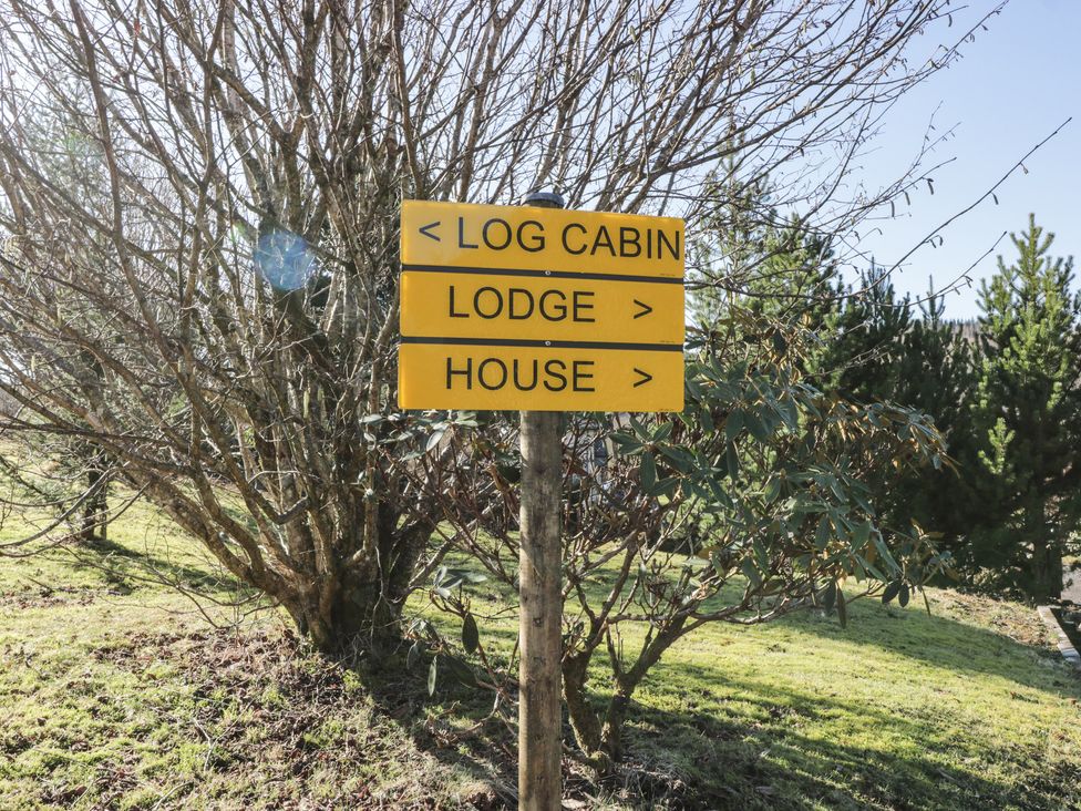 A wooden signpost with directions to log cabin left lodge and house right with trees and grass in the background at The River Lodge in Oban
