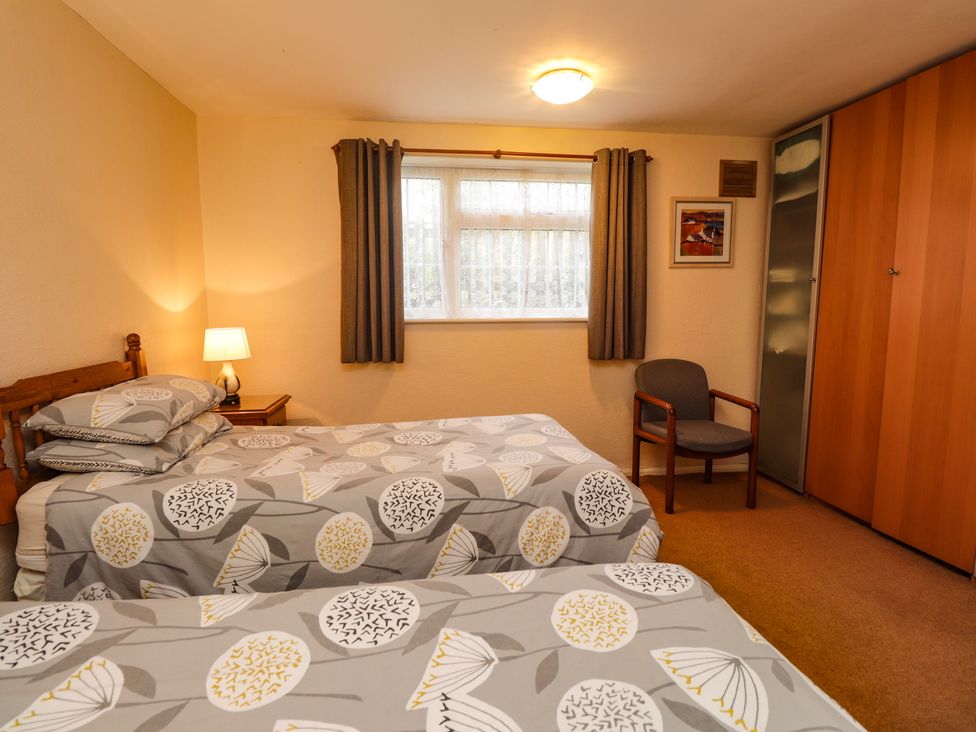 A bedroom with two single beds a nightstand with lamp a chair and wardrobes at Old Post Office Ruckinge near Hamstreet