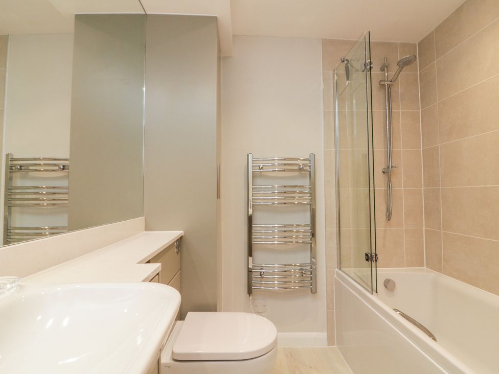 A bathroom with a sink toilet heated towel rail and bathtub with shower at 34 The Salcombe in Salcombe