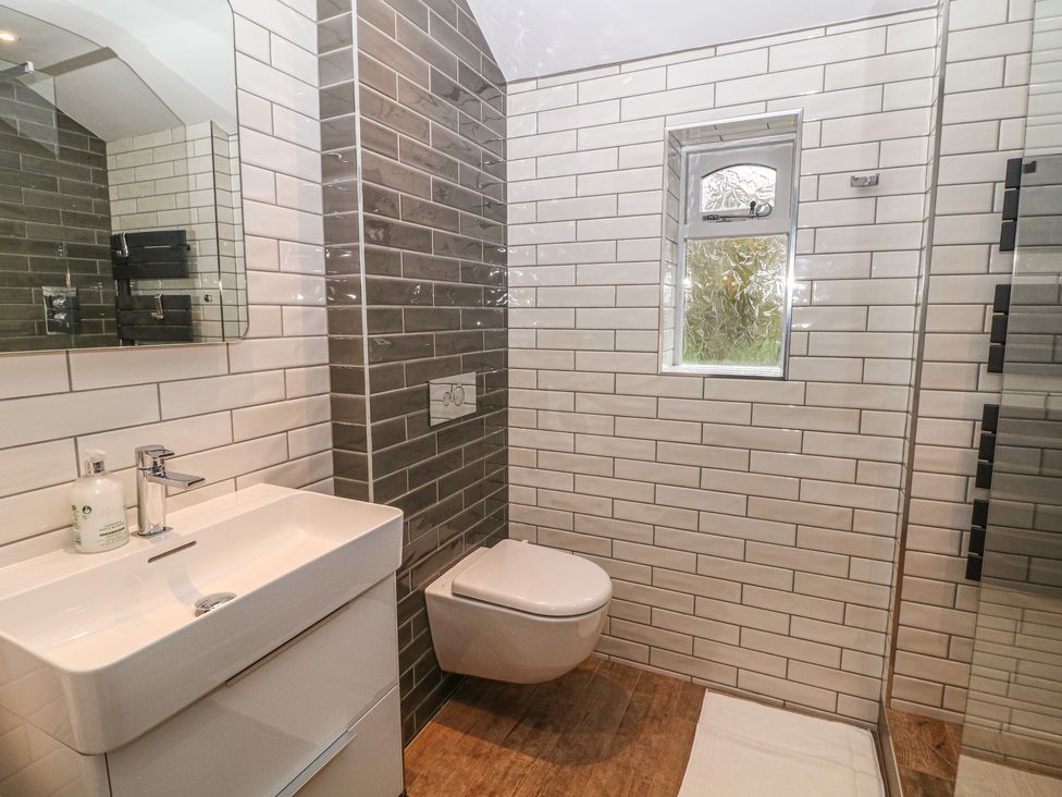 A bathroom with a wall mounted toilet sink and a small window at Hockerley Cottage in Whaley Bridge