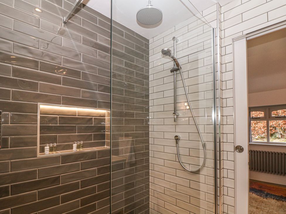 A tiled shower area with a rain shower head and handheld shower at Hockerley Cottage in Whaley Bridge