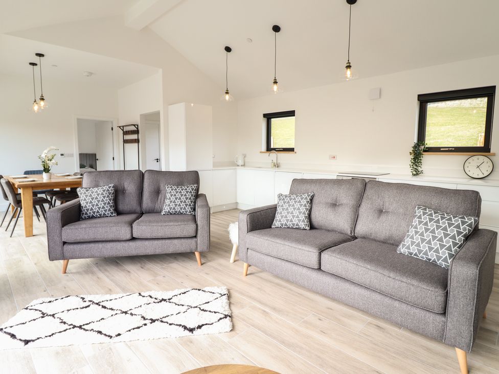 A living room with gray sofas and a dining table with chairs at The Sheep Shed in Llanrhaeadr-Ym-Mochnant