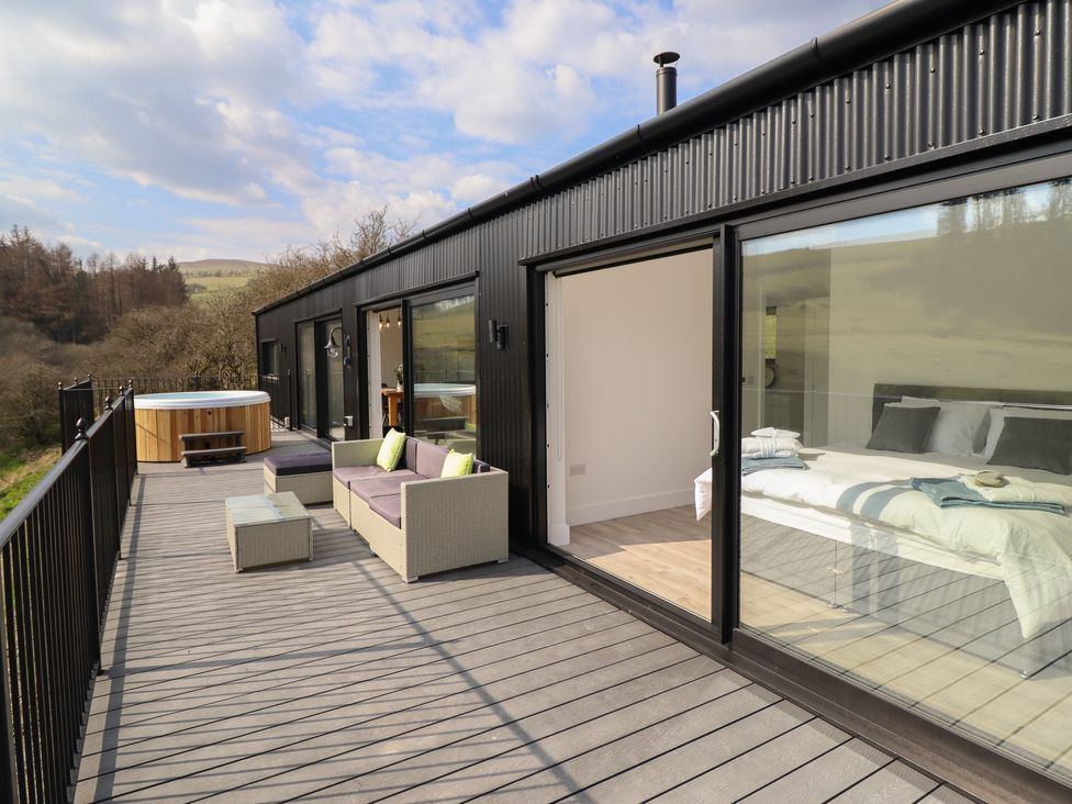 A balcony with outdoor seating and a hot tub outside bedrooms at The Sheep Shed in Llanrhaeadr-Ym-Mochnant