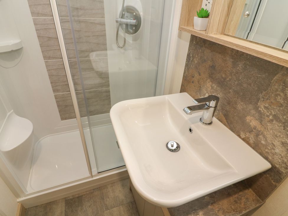 A bathroom with a white sink and a shower enclosure at Lancaster Lodge in South Lakeland Leisure Village