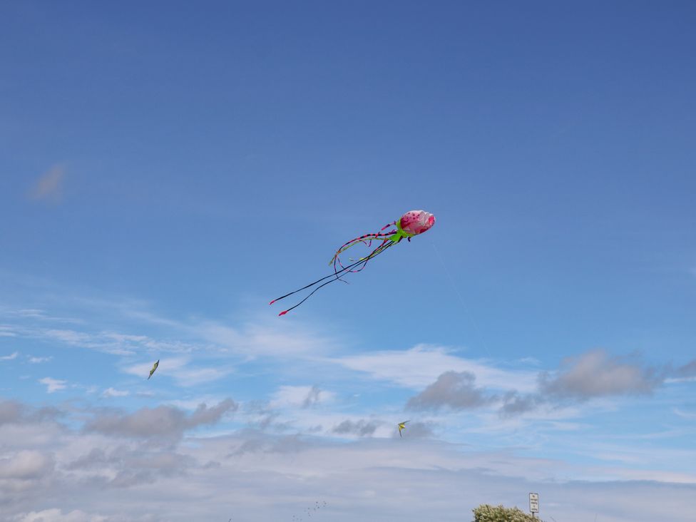 A pink kite flying in the blue sky with some clouds at Harbour View Poole in Poole
