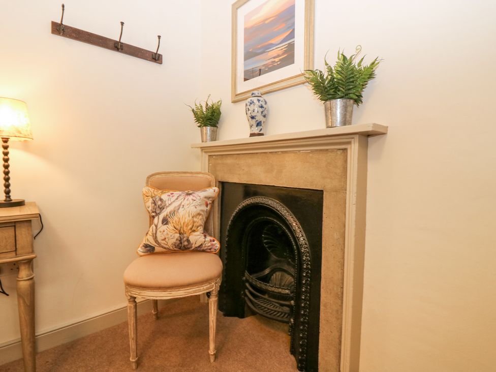 A corner with a chair and cushion next to a fireplace with plants and a vase on the mantel at Pear Cottage - Priorwood Garden in Melrose