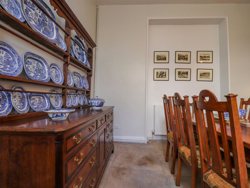 A dining room with a wooden sideboard displaying blue and white plates and wooden chairs around a table at Windyridge in Settle
