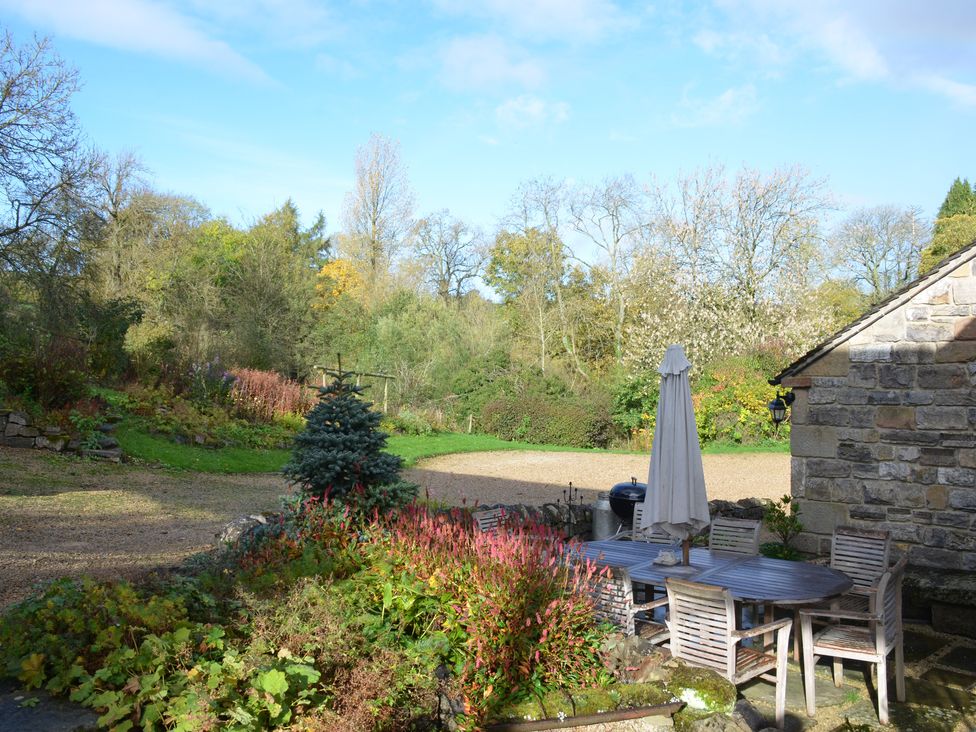 A garden with an outdoor dining table and chairs near a stone building at Green Farm Stables in Hognaston near Carsington Water