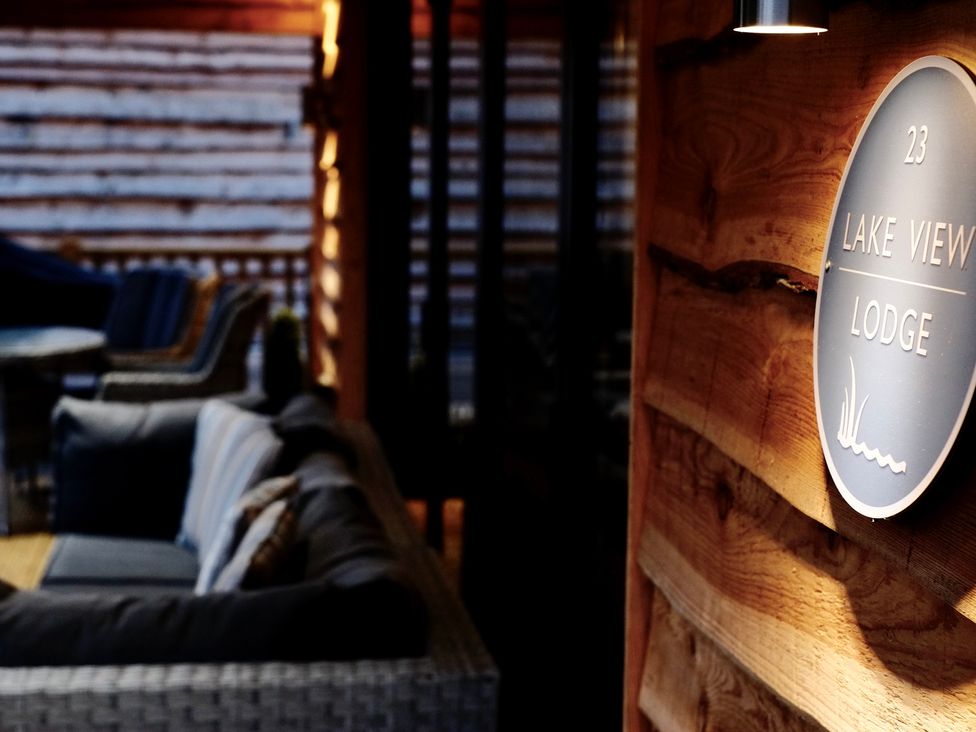 An outdoor seating area with sofas and chairs with a wooden wall and a sign that says Lake View Lodge at Lake View Lodge in Thorpe-On-The-Hill
