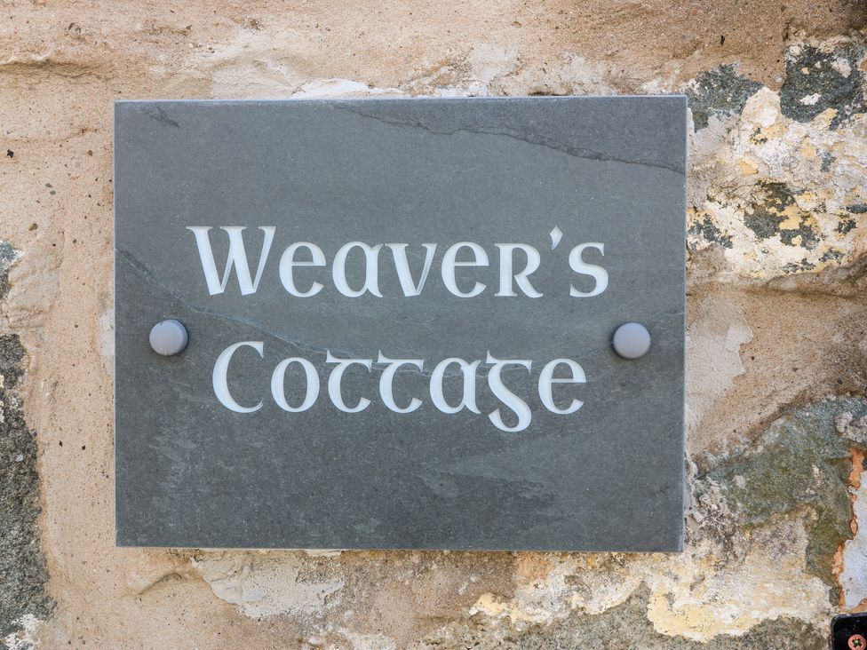 A stone plaque with the text Weavers Cottage mounted on a rough stone wall at Weavers Cottage Tremadog
