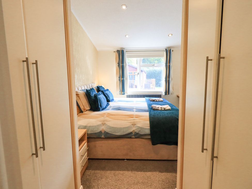 A bedroom with a double bed with pillows and blankets between two wardrobes at Rydal Lodge in Grasmere 24 White Cross Bay near Windermere