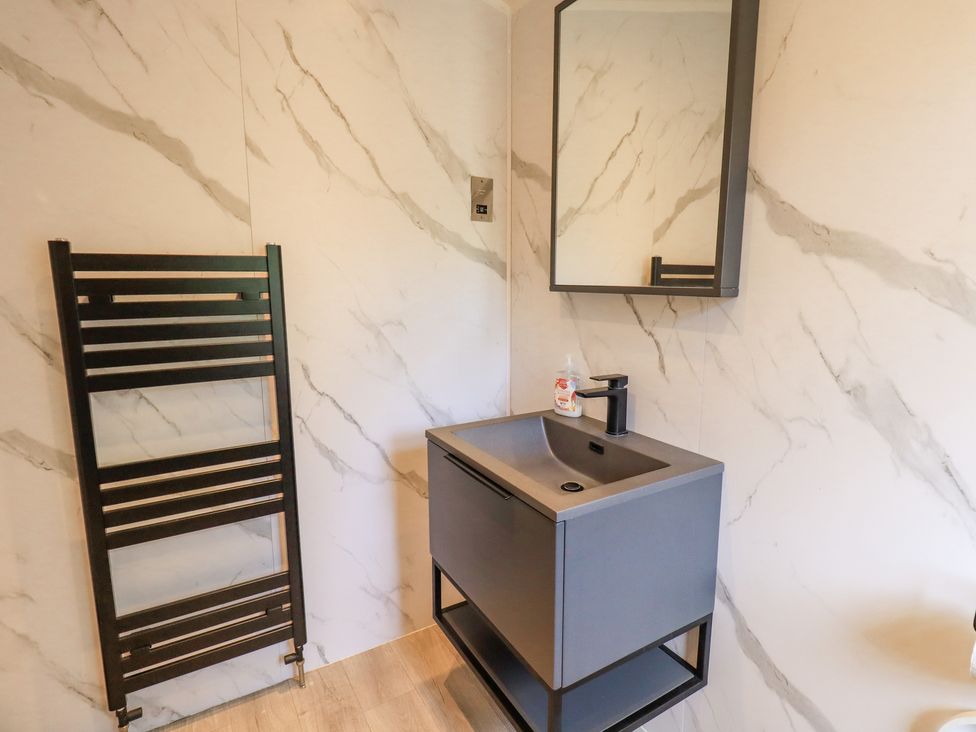 A bathroom with a black towel rack a dark gray sink cabinet and a mirror at Rydal Lodge Grasmere 24 White Cross Bay near Windermere