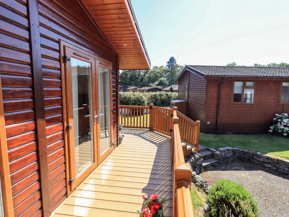 A wooden deck with railing outside a wooden cabin with glass double doors at Robins Nest in Bowness 71 White Cross Bay near Windermere