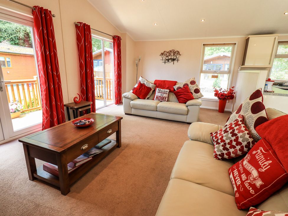 A living room with two beige sofas red cushions a wooden coffee table and red curtains at Robins Nest Bowness 71 White Cross Bay near Windermere