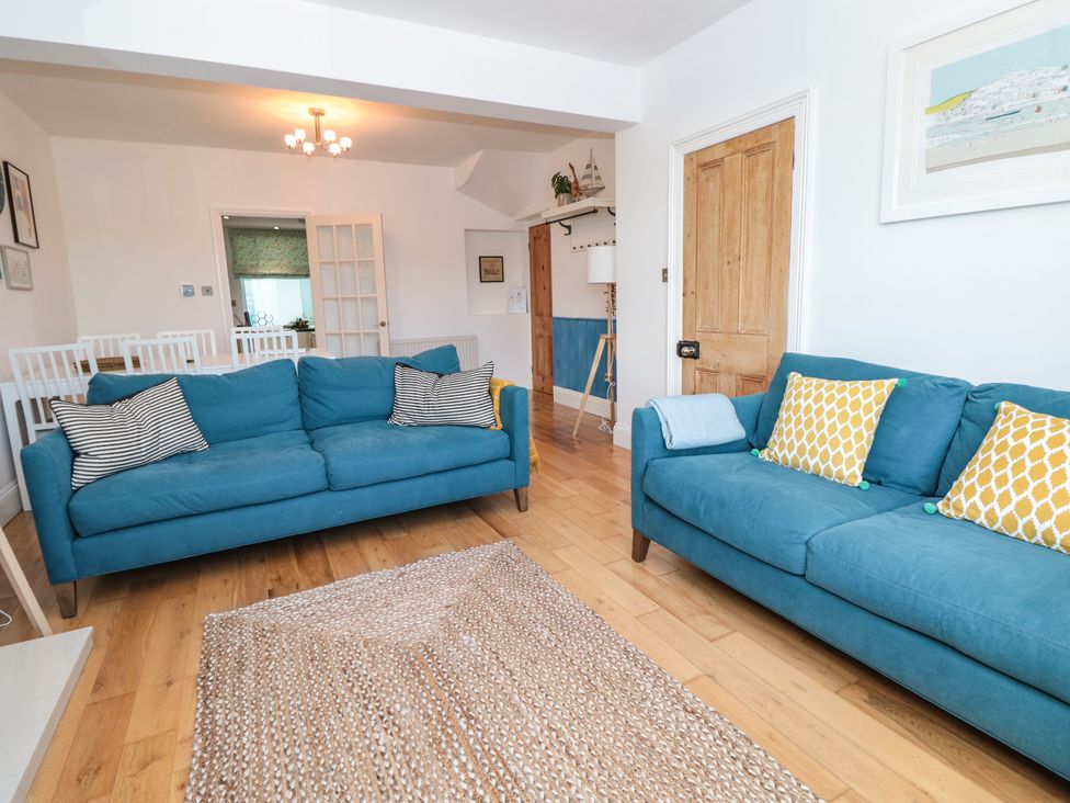 A living room with two blue sofas and a woven rug at Seascape Dartmouth