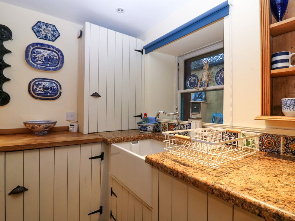 A kitchen corner with a sink countertop cabinets and blue and white decorative plates at Wonderland Cottage in Newburgh Fife