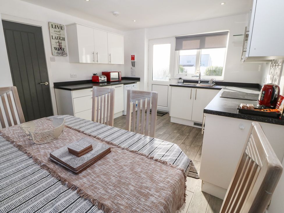 A kitchen with a dining table and chairs toaster microwave and cabinets at Beach Reach in Valley