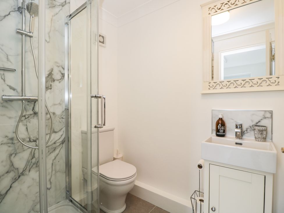 A bathroom with a shower, toilet, sink, and mirror at The Stable House in Sherborne