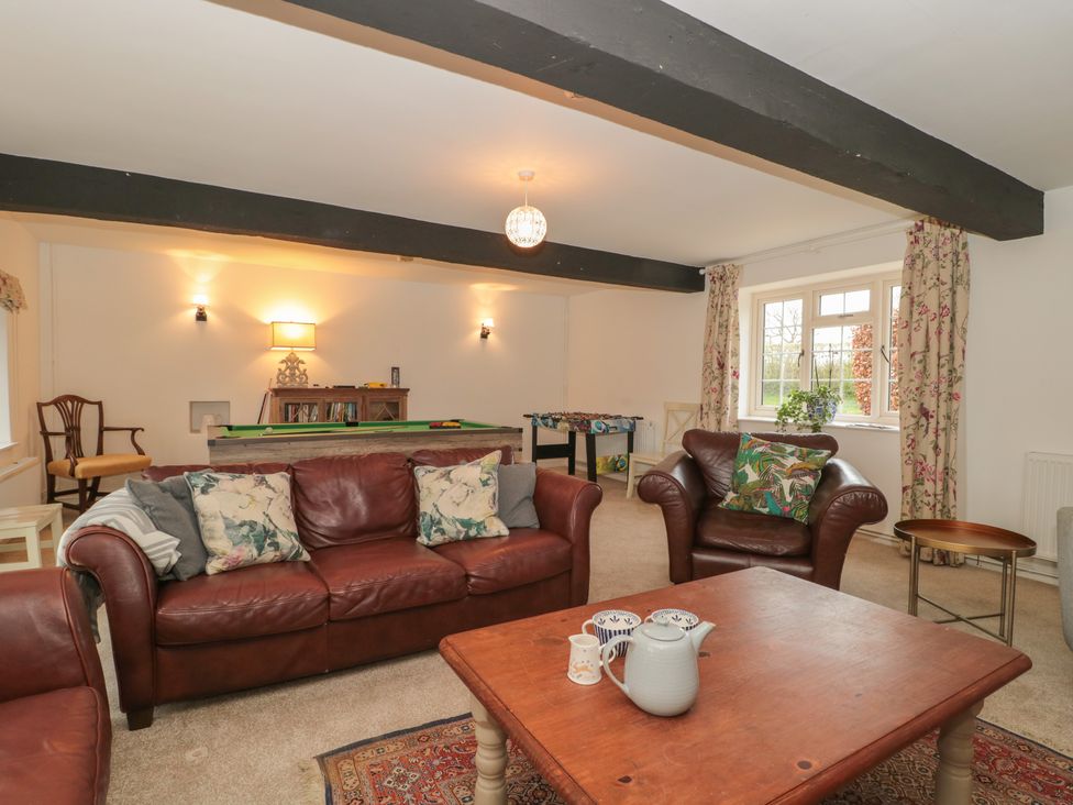 A living room with leather sofas a wooden table a pool table and a foosball table at The Stable House in Sherborne