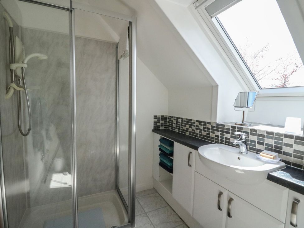 A bathroom with a shower enclosure sink and cabinet under a skylight window at Upper Brackendale in Taynuilt