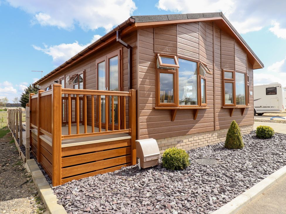 A wooden mobile home with a small porch and gravel landscaping at 12 Bucklesham Park in Bucklesham near Trimley St Martin