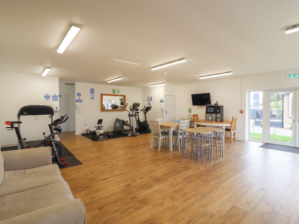 A gym area with exercise equipment and tables with chairs at 12 Bucklesham Park in Bucklesham near Trimley St Martin