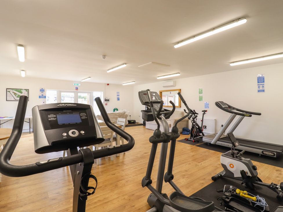 A gym room with exercise bikes elliptical machine treadmill and weights at 12 Bucklesham Park in Bucklesham near Trimley St Martin