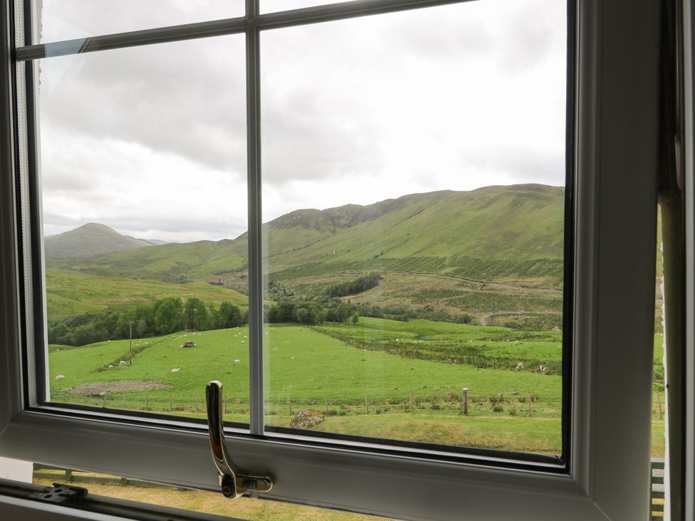 A green hilly landscape with sheep viewed through a window at Brae Mhor Cottage in Fort William