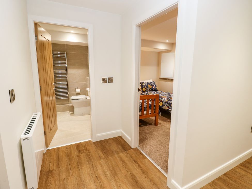 A hallway with wood flooring leading to a bathroom and a bedroom at 2 Barn Cottages in Norwood Green
