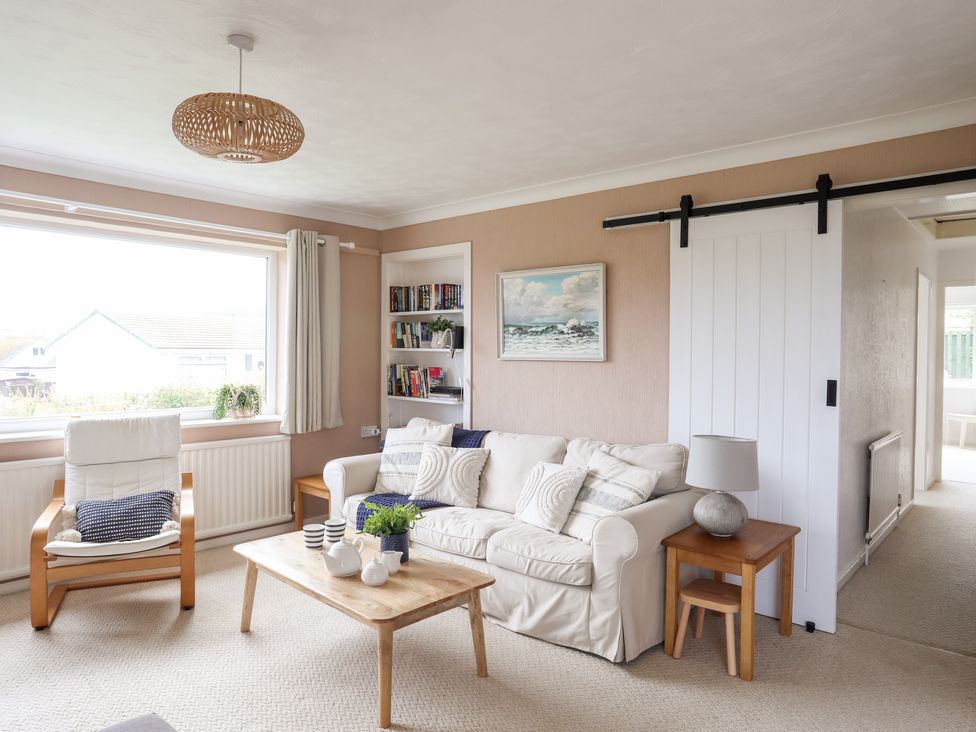 A living room with a white sofa and wooden coffee table near a window at Ty Bedw in Benllech