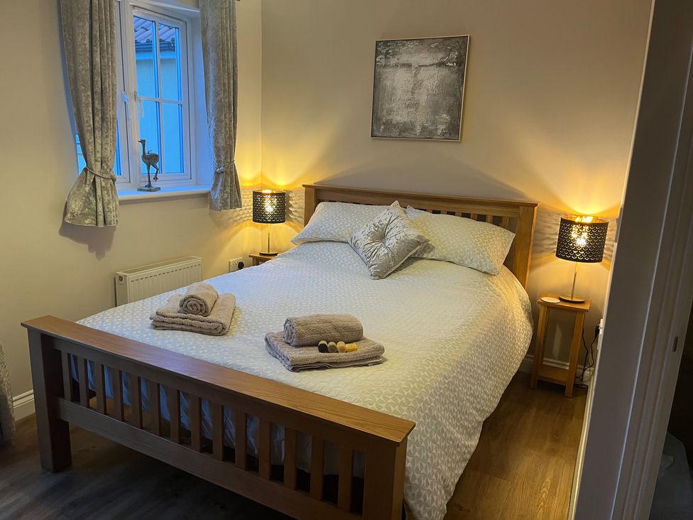 A bedroom with a wooden bed frame bedside tables with lamps and a window at Gone Crabbing The Bay Filey