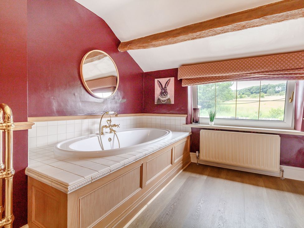 A bathroom with a built-in bathtub under a window showing outside greenery at Fence House in Fence