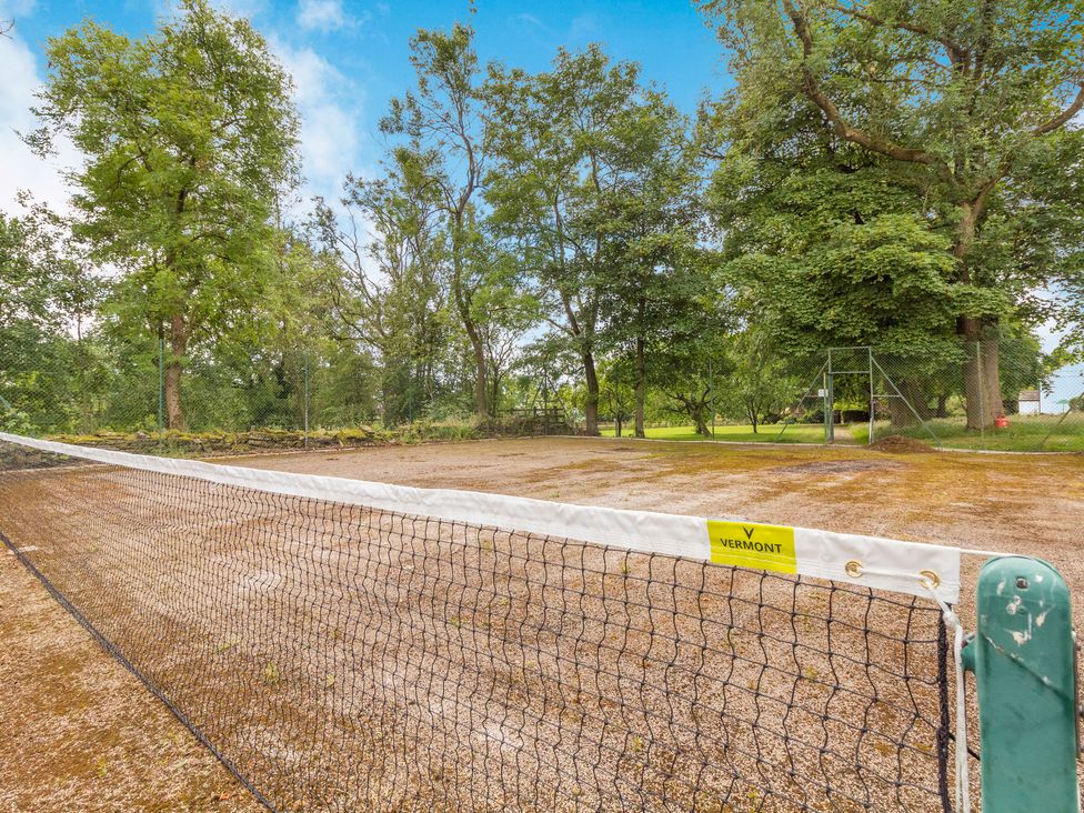 An outdoor tennis court with a net surrounded by trees at Fence House in Fence