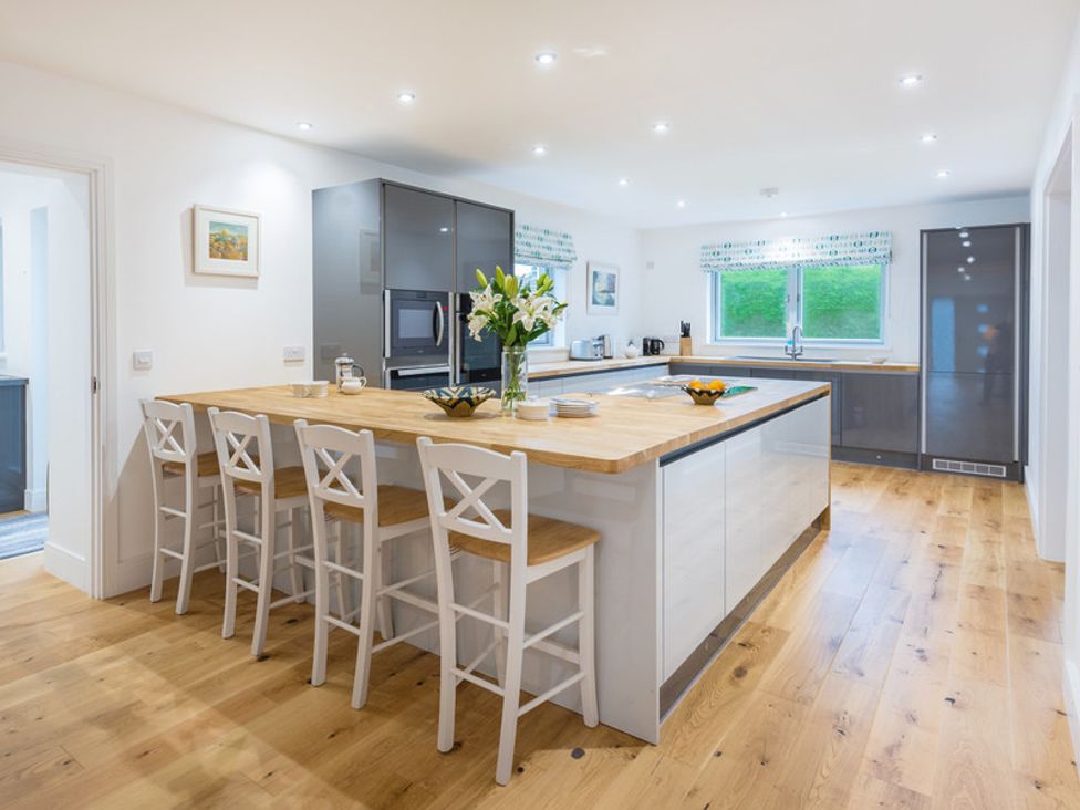 A kitchen with a wooden floor and island with bar stools and cabinets at Artemis in Rock