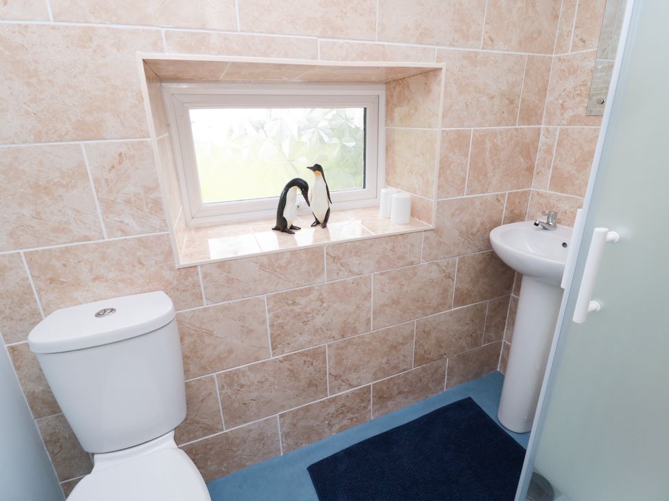 A small bathroom with a toilet sink window and penguin figurines on the window sill at 1 Roddam Rigg Cottage Roddam near Wooler