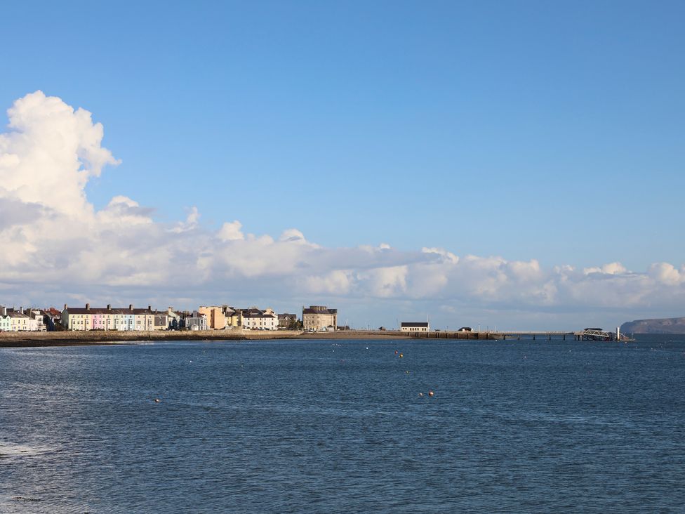 A coastal town with colorful buildings along the shoreline and a pier extending into the sea at Tegfryn Bach in Llangoed near Beaumaris